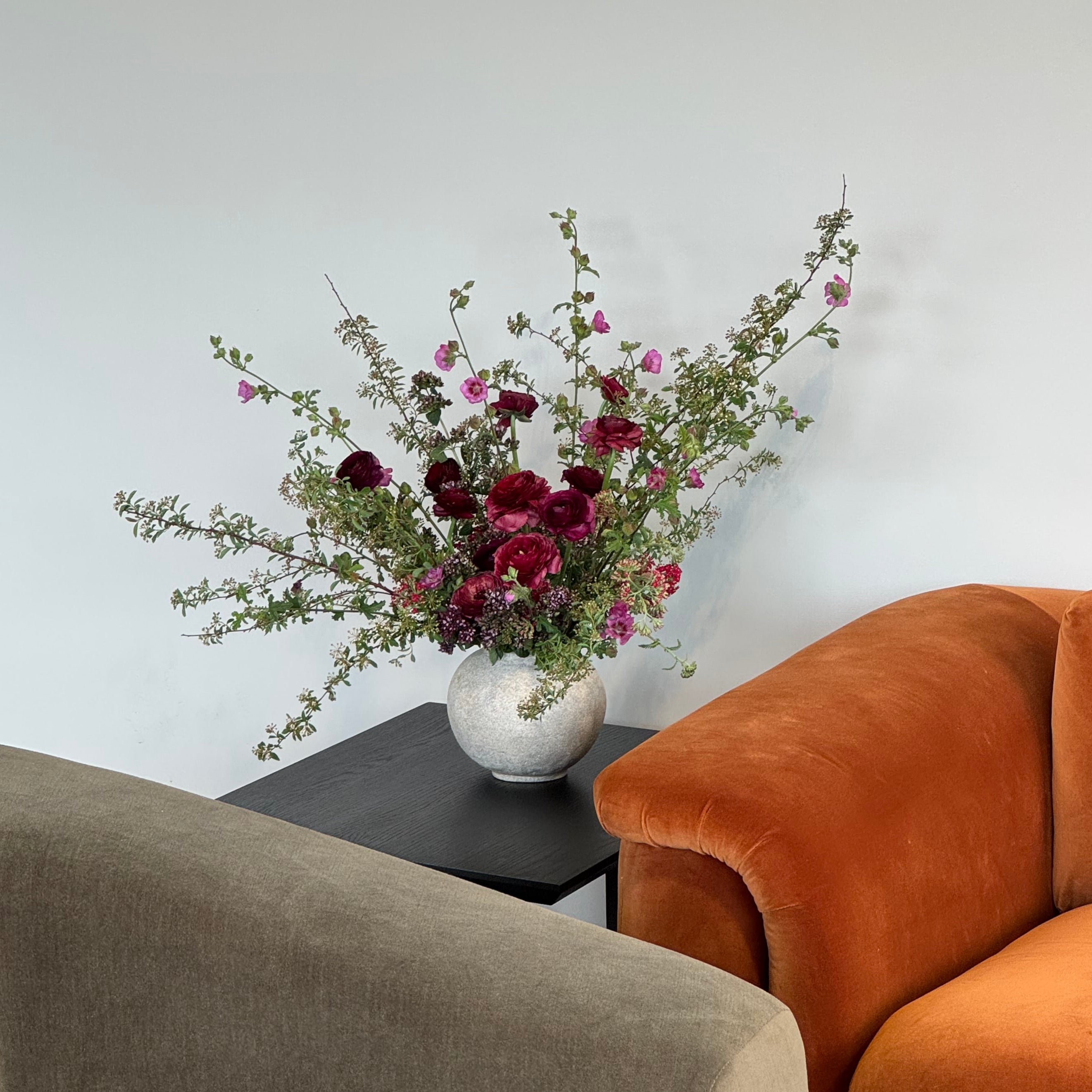 Floral arrangement on a white surface next to a brown chair