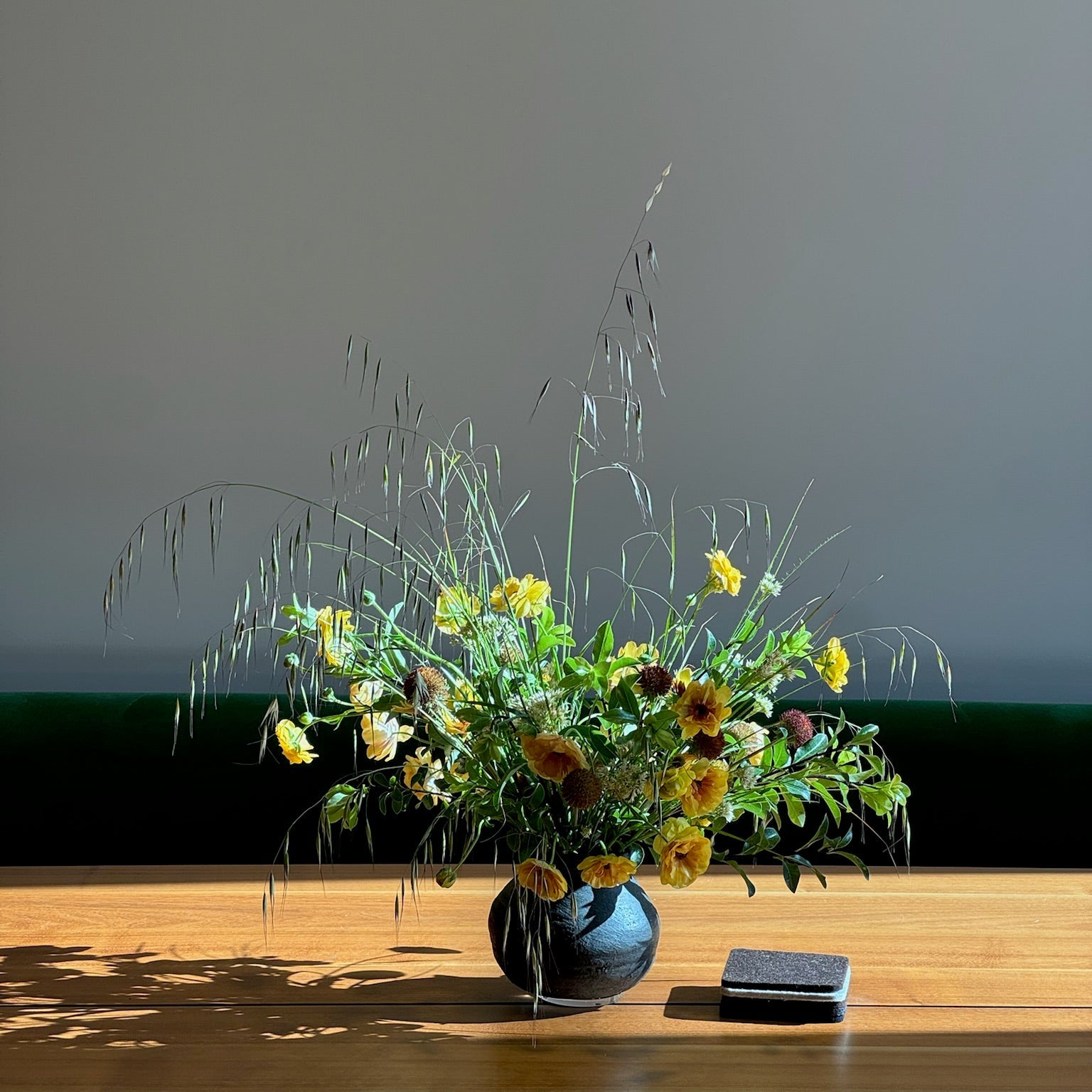 Floral arrangement in a vase on a wooden surface with a plain background