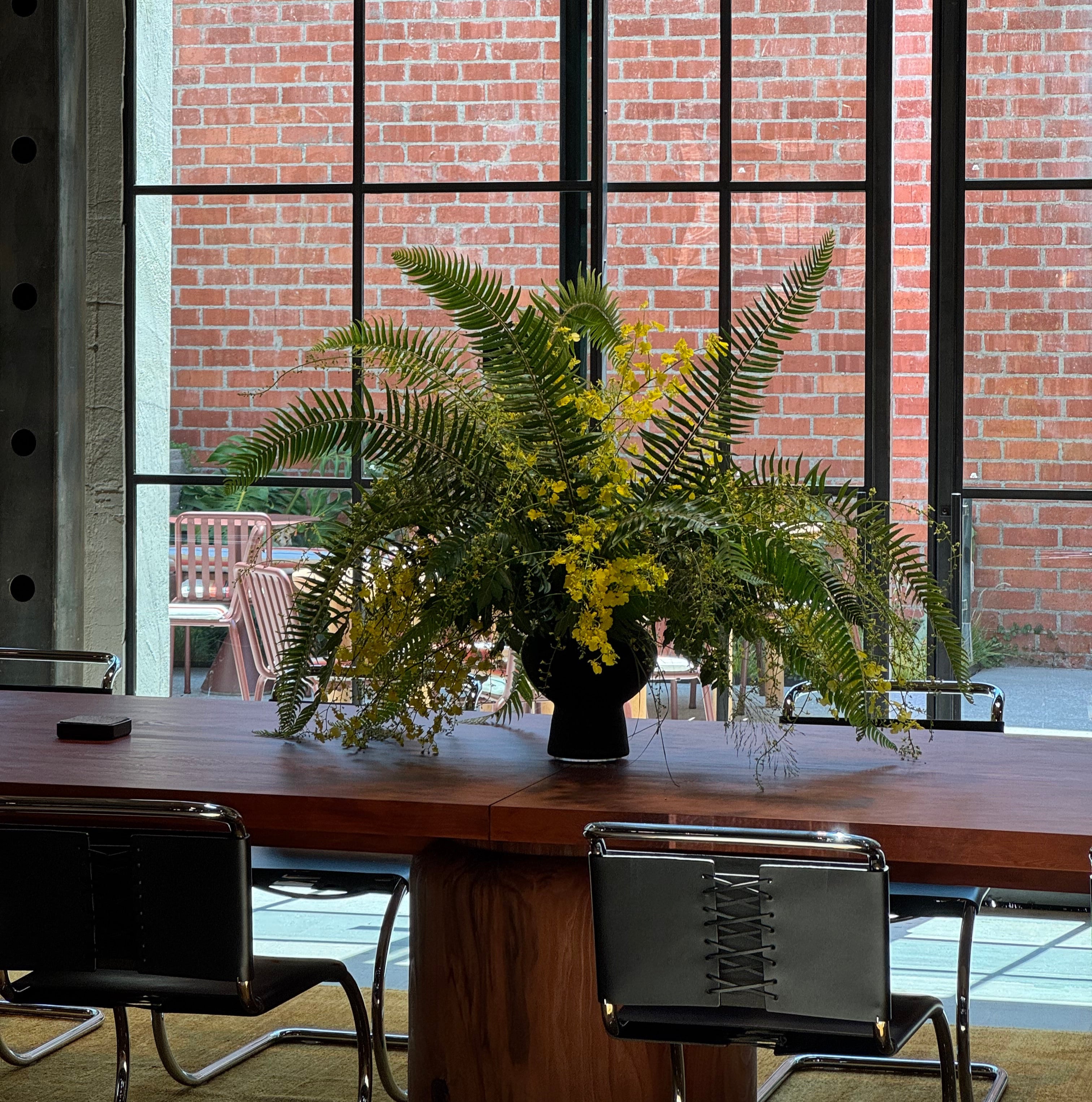 Floral arrangement on a table with a brick wall and window in the background