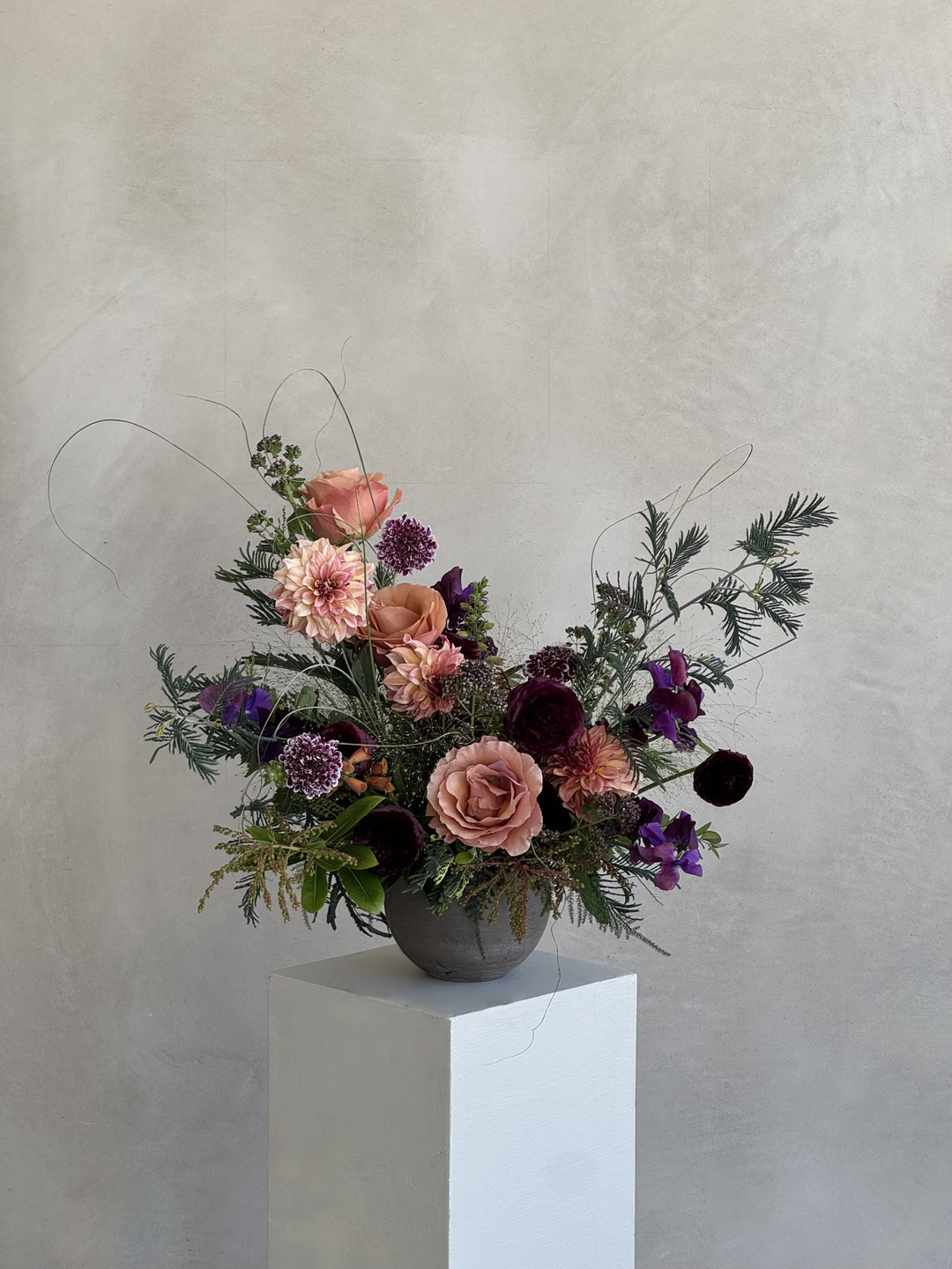 Floral arrangement on a white pedestal against a light gray background