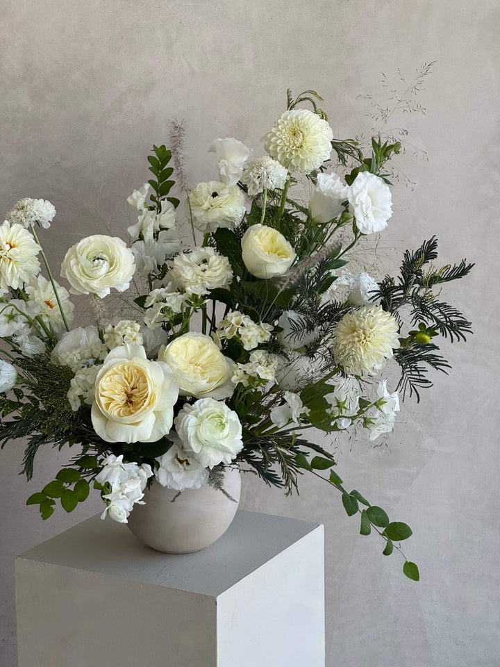 Bouquet of white and yellow flowers in a vase on a light gray background
